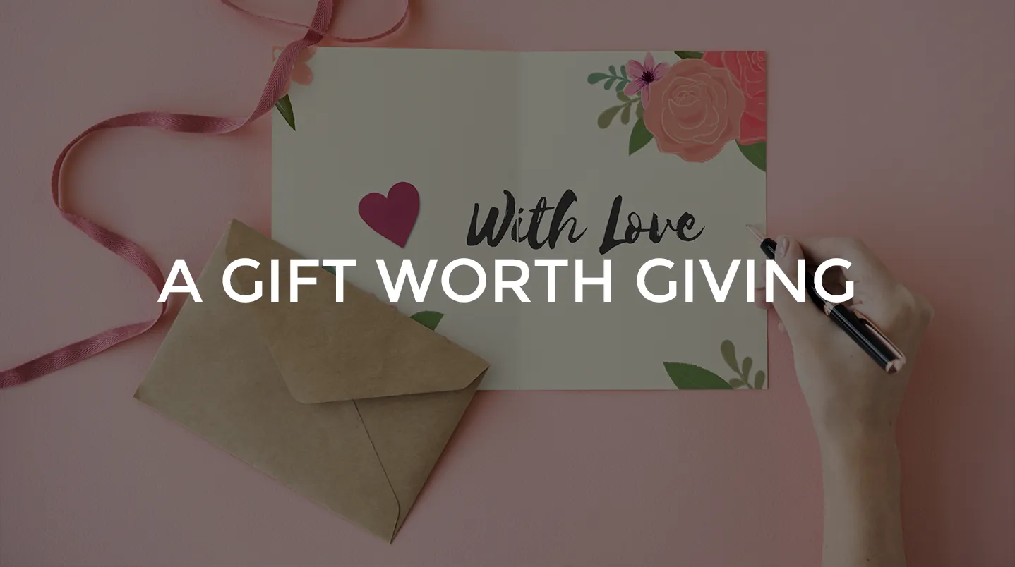 A hand writing in a With Love card beside an envelope