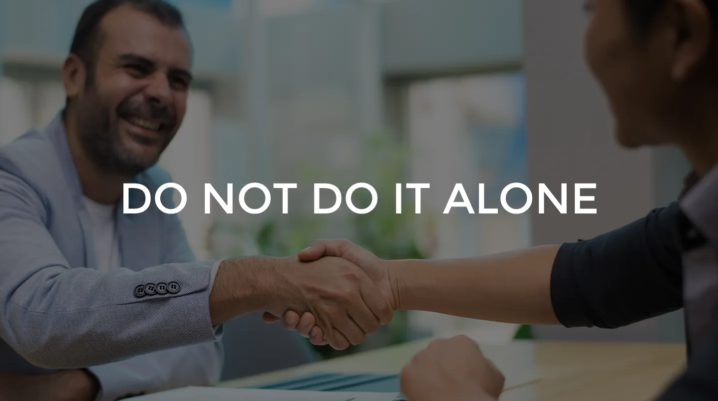 A smiling man shaking hands across a desk